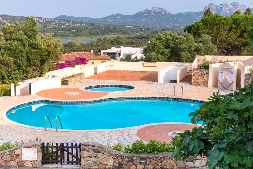 a large swimming pool with a stone wall around it at trilocale con piscina in Arzachena