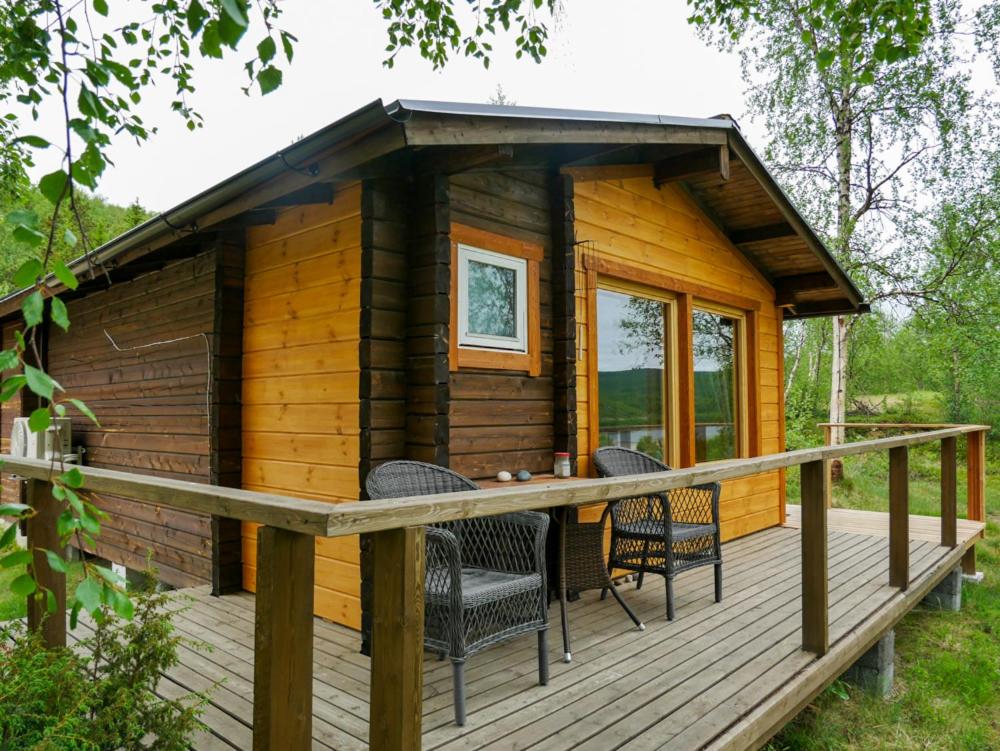 Cabaña de madera con sillas en una terraza en Tenon maisemamökit, en Utsjoki