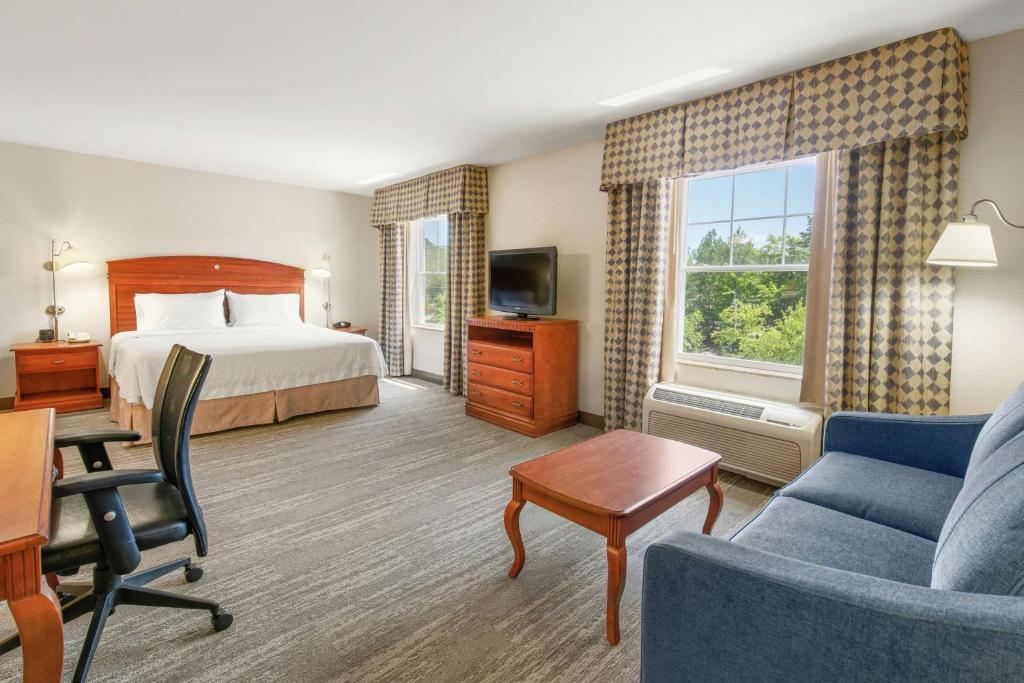 a hotel room with a bed and a desk and a couch at Hampton Inn & Suites North Conway in North Conway