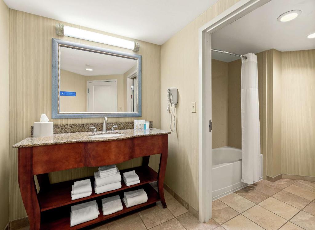a bathroom with a sink with a mirror and a tub at Hampton Inn & Suites North Conway in North Conway