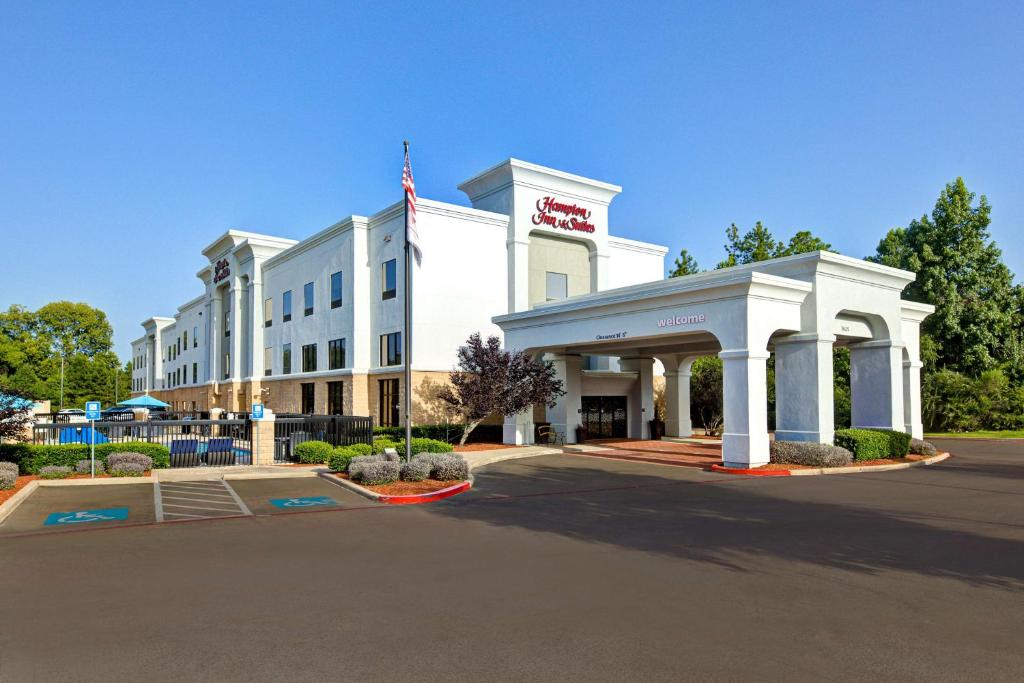 a white hotel with an american flag in front of it at Hampton Inn & Suites Nacogdoches in Nacogdoches