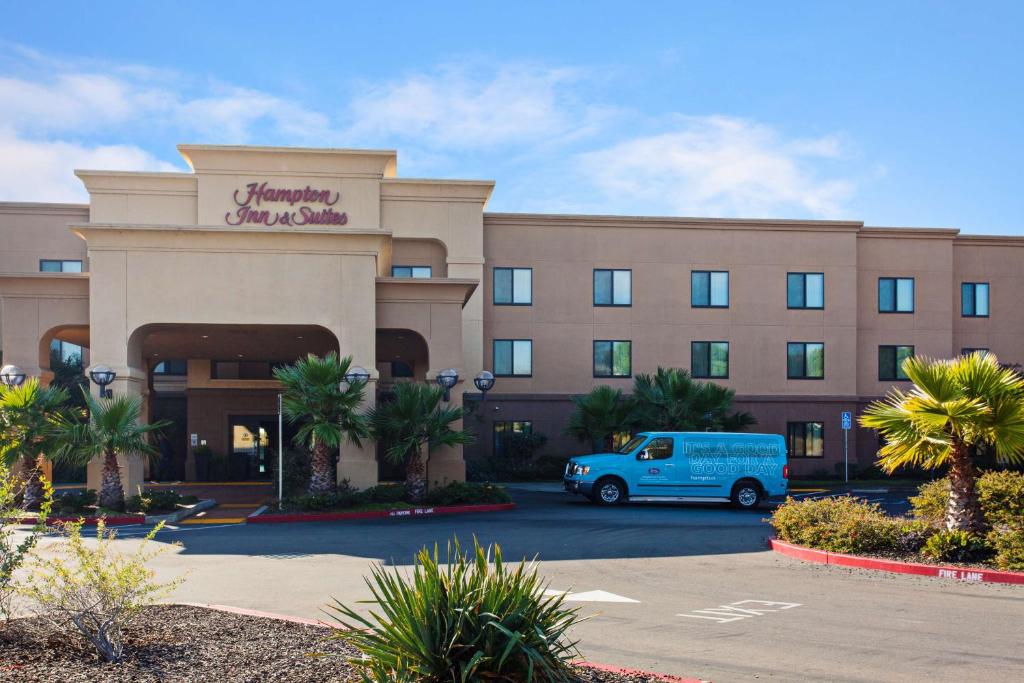 un hotel con una furgoneta azul estacionada en un estacionamiento en Hampton Inn & Suites Oakland Airport-Alameda, en Alameda