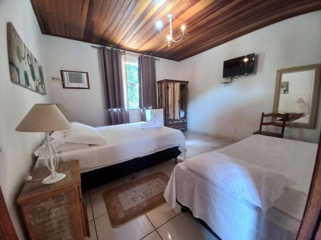 a bedroom with two beds and a lamp and a tv at Pousada Green Garden in Engenheiro Paulo de Frontin