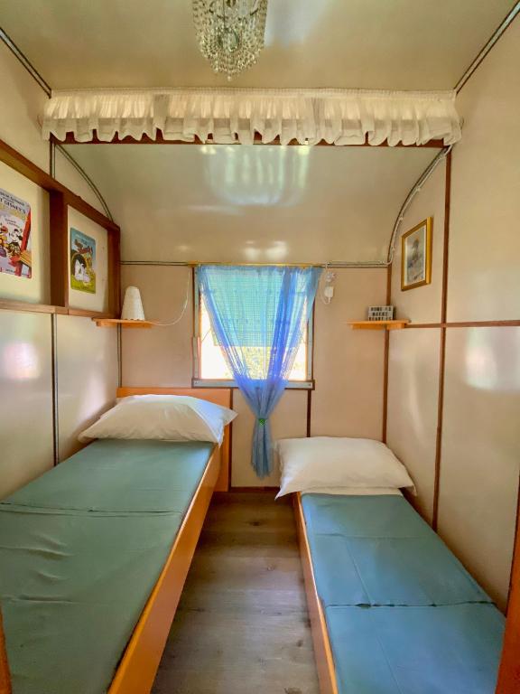 two beds in a small room with a window at Azienda agricola Della Mezzaluna in Stiava