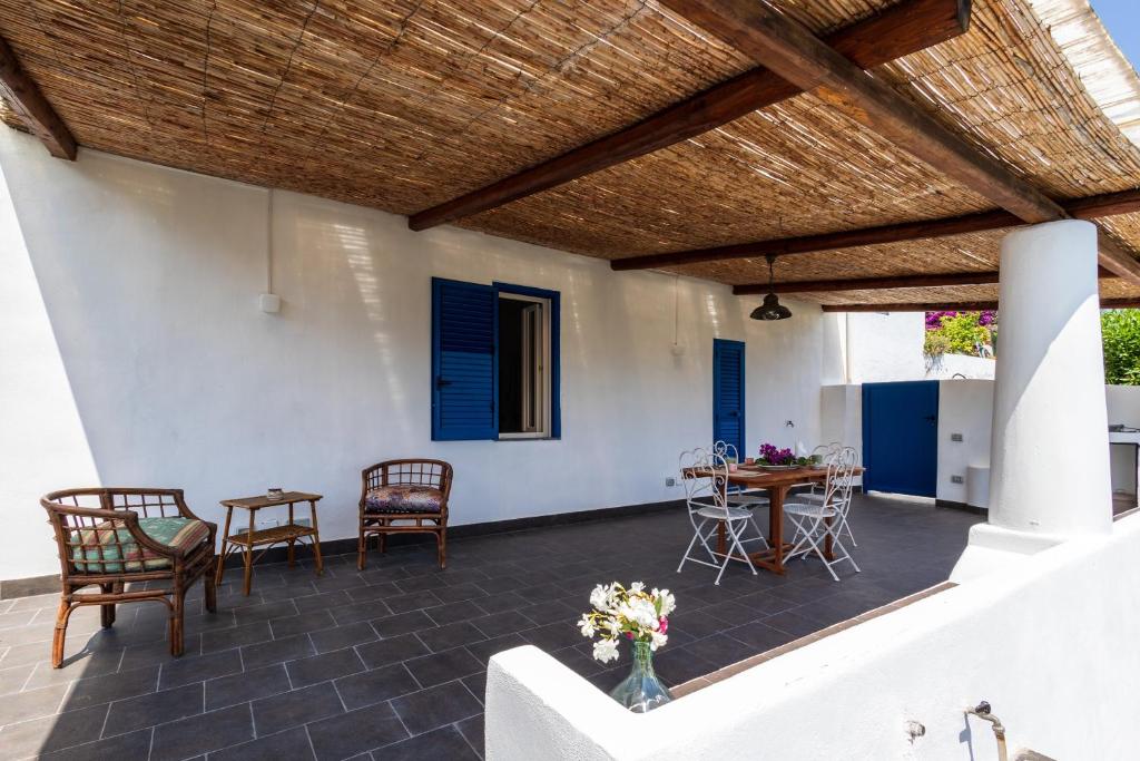 a patio with a wooden roof and chairs and a table at La casa del Geologo in Stromboli