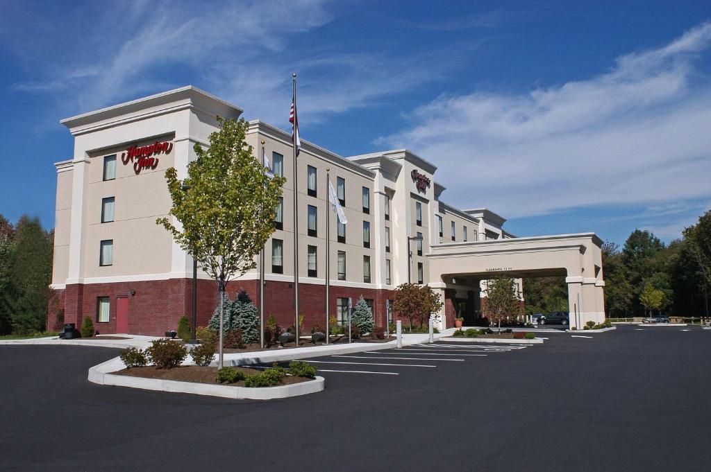 a large white building with a flag on top of it at Hampton Inn Raynham-Taunton in Raynham