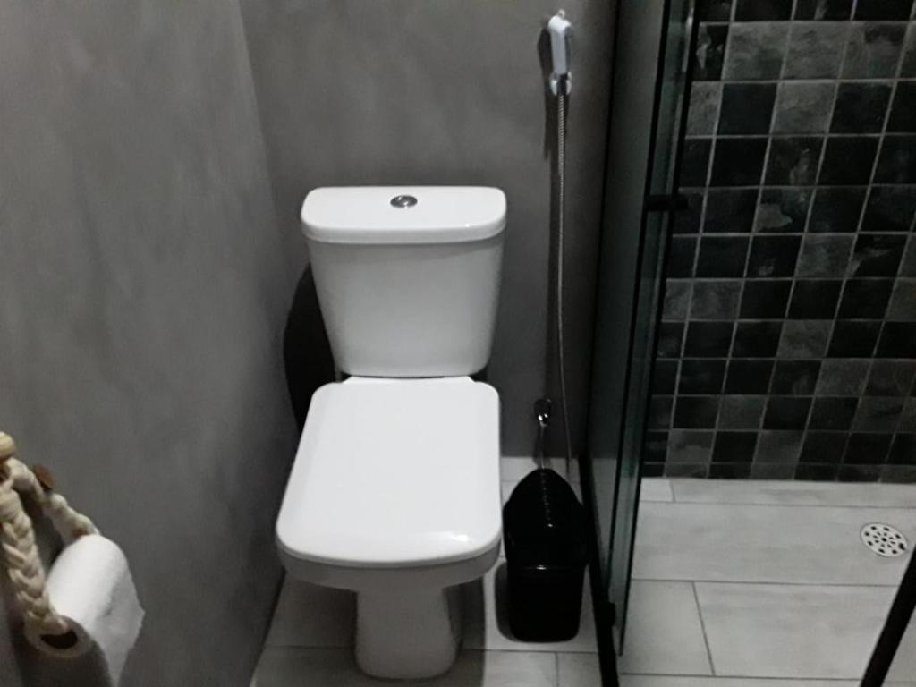 a bathroom with a white toilet and a shower at Suíte 100m da praia e academia inclusa dias de semana in Maceió