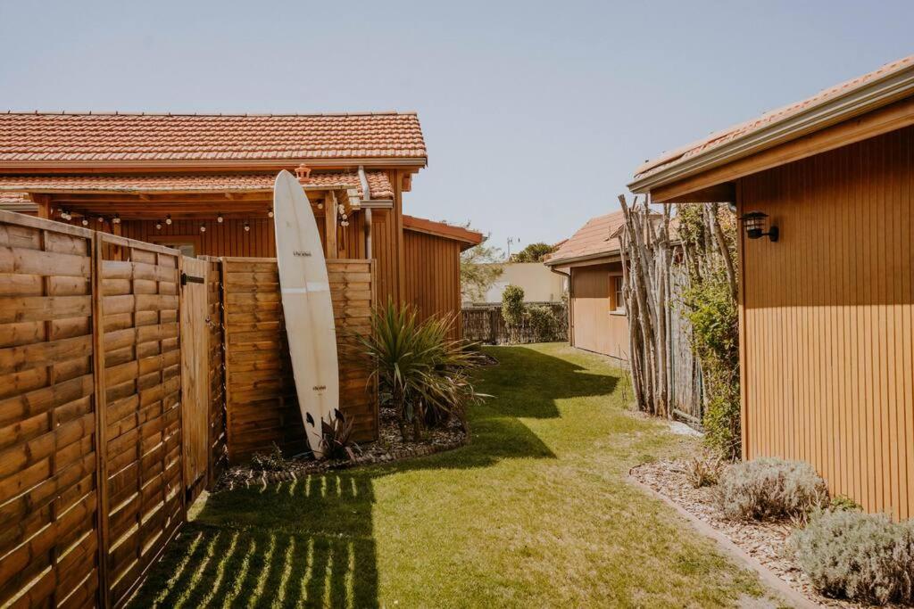 a surfboard leaning against a fence next to a house at La cabane de Mamie classée 4 étoiles à 150m de la plage 2 chambres 3 lits in Biscarrosse