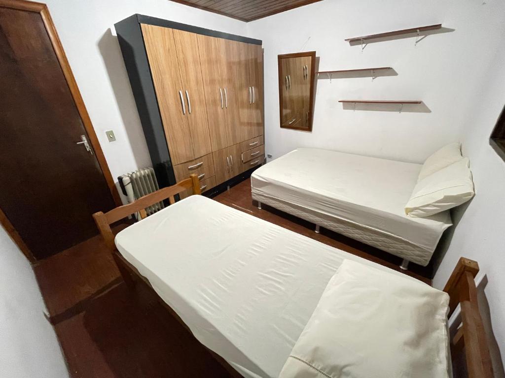 a small room with two beds and a cabinet at Casa com excelente localização in Campos do Jordão