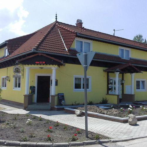 una casa amarilla con un cartel delante en Malom Fogadó, en Balatonboglár