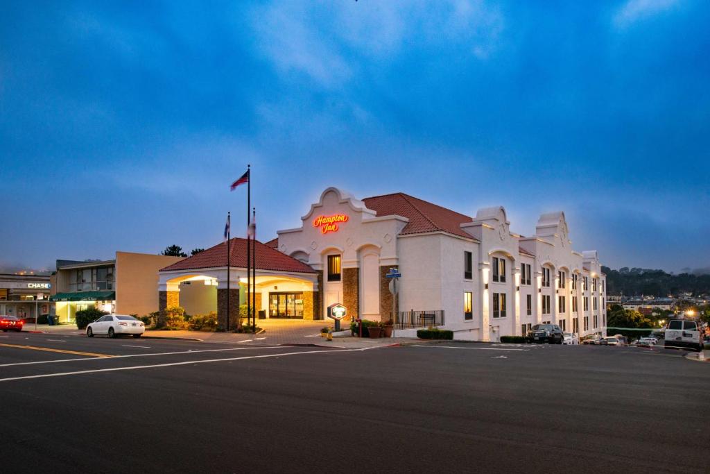 Hampton Inn San Francisco - Daly City في دالي سيتي: مبنى ابيض كبير عليه لافته