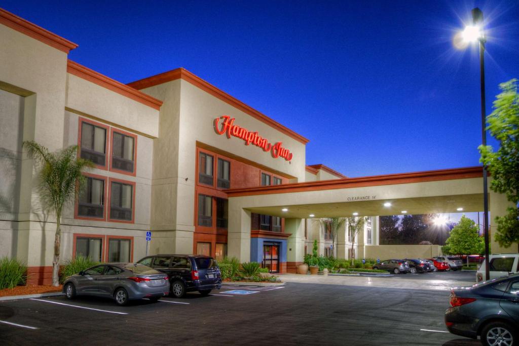 una vista frontal de un hotel con coches aparcados en un aparcamiento en Hampton Inn Fremont, en Fremont