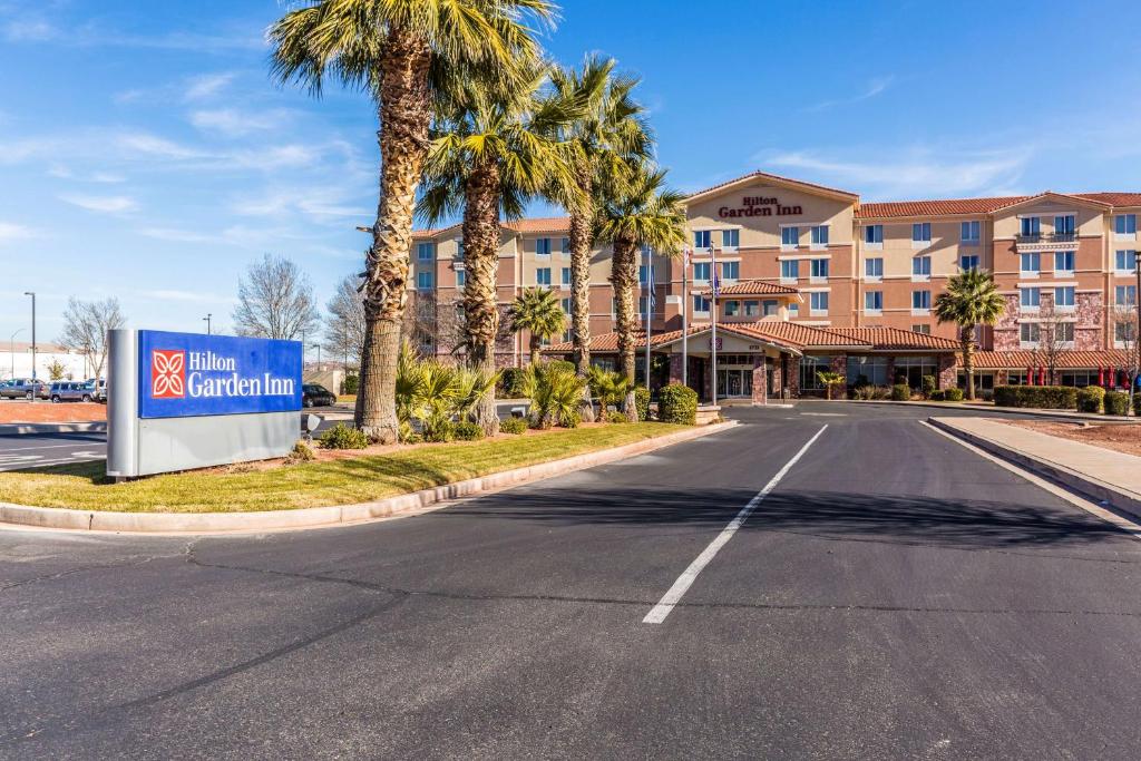 an empty street in front of a hotel with palm trees at Hilton Garden Inn St. George in St. George