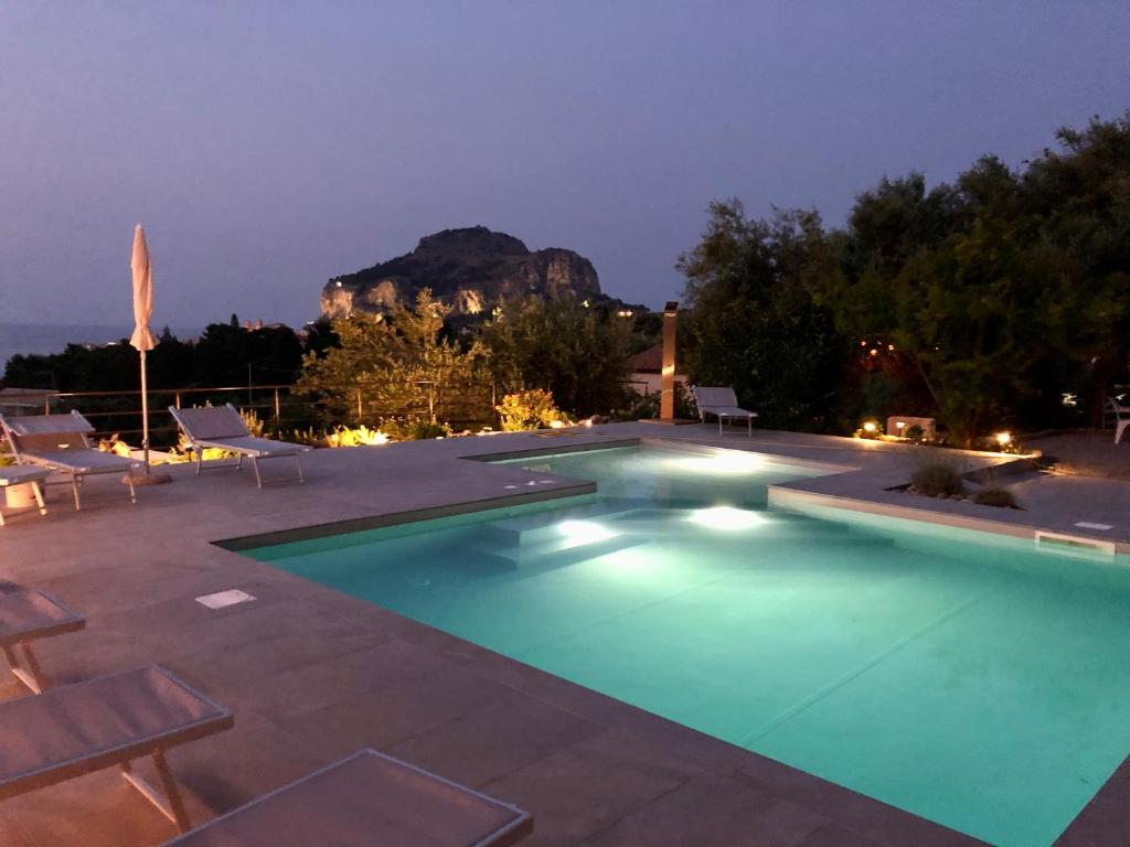 a swimming pool at night with a mountain in the background at Casa Miraflores in Cefalù