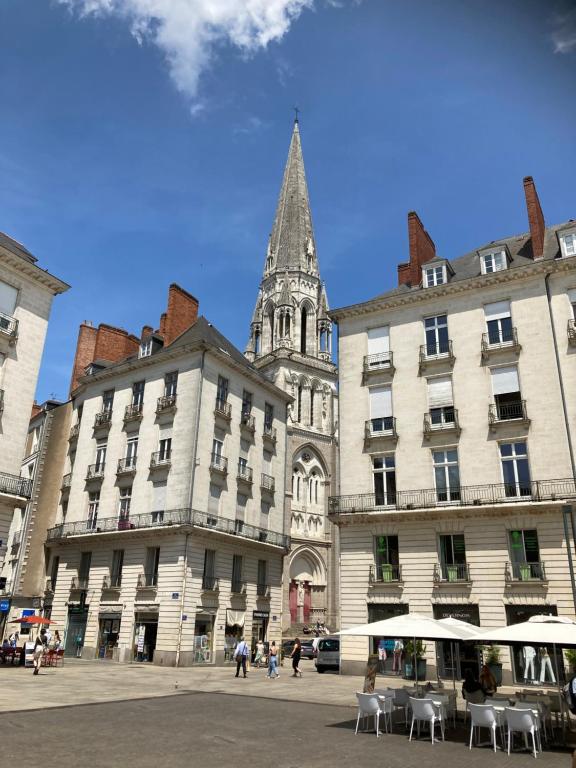 un groupe de bâtiments avec une cloche d'église en arrière-plan dans l'établissement Le Bretagne, 3 chambres, à Nantes