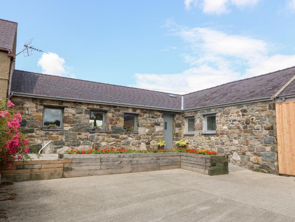 a stone house with flowers in front of it at Y Beudy in Caernarfon