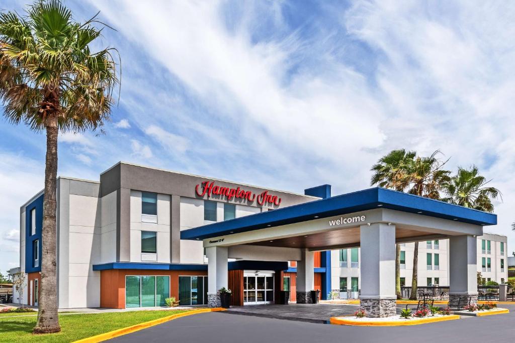 a hotel with a palm tree in front of a building at Hampton Inn Sulphur in Sulphur