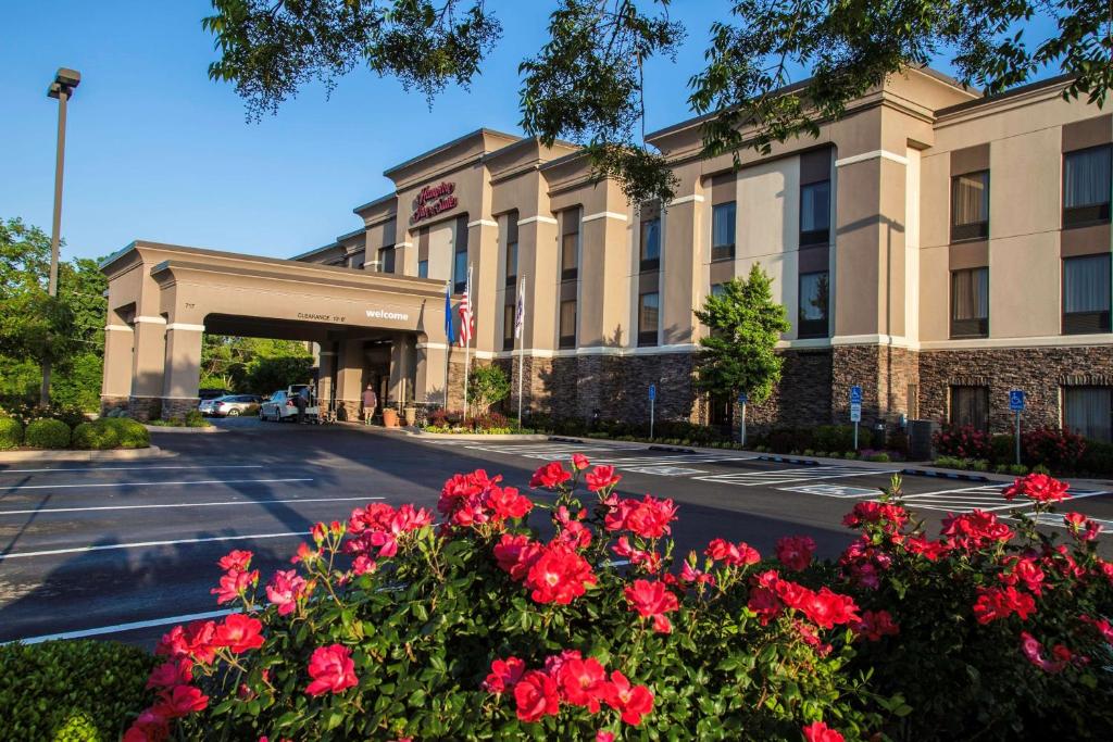 a hotel with red flowers in front of a building at Hampton Inn & Suites Stillwater in Stillwater