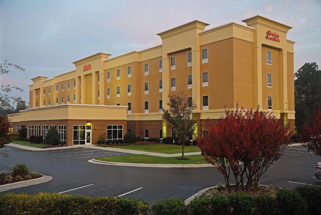 a large yellow building with a parking lot at Hampton Inn & Suites Southern Pines-Pinehurst in Aberdeen