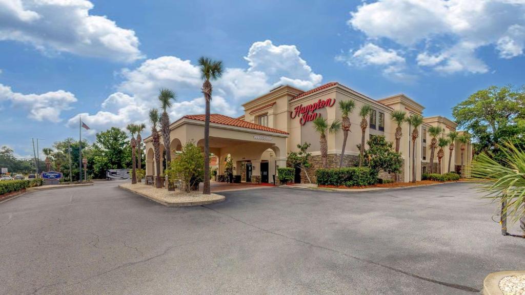 圣西蒙斯岛Hampton Inn St. Simons Island的停车场内棕榈树的绿色建筑