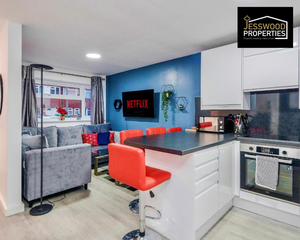 a kitchen with a counter and a red chair at Spacious 5 Bedroom, 3 Bath House by Jesswood Properties Short Lets For Contractors, With Free Parking Near M1 & Luton Airport in Luton