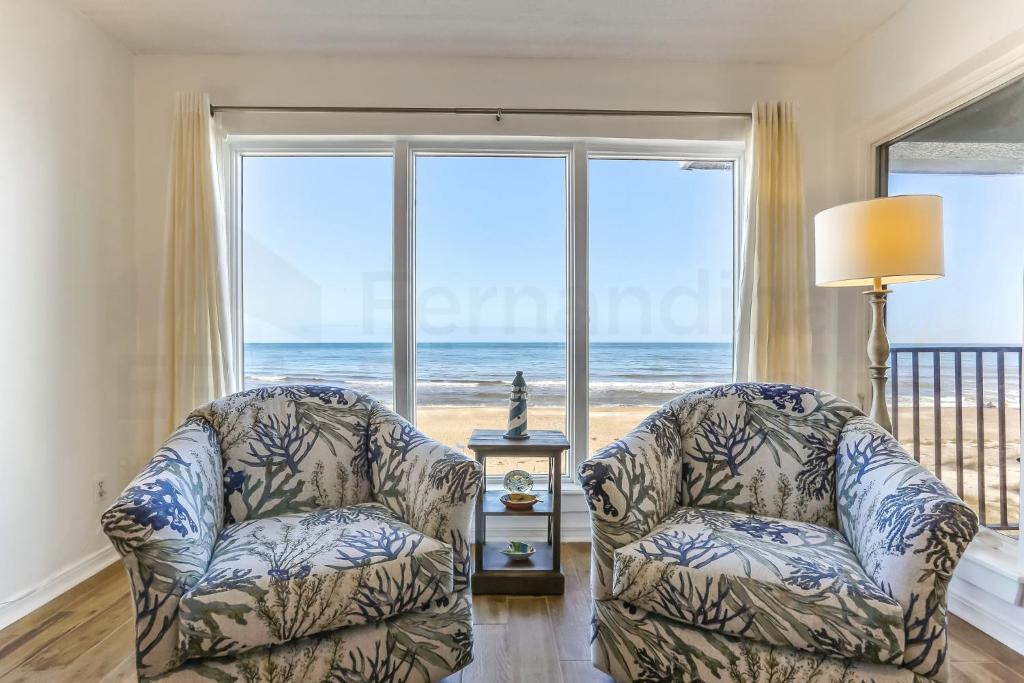 two chairs in a living room with a view of the ocean at Oceans Of Amelia - 309 in Fernandina Beach