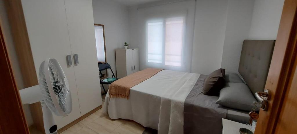 a bedroom with a bed and a chair and a fan at El Patio de Lucy in Puerto de Sagunto