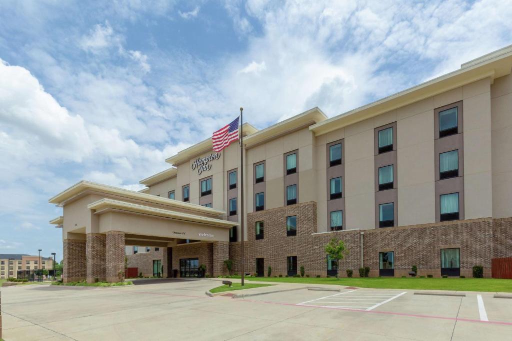 a hotel with an american flag in front of it at Hampton Inn Texarkana in Texarkana