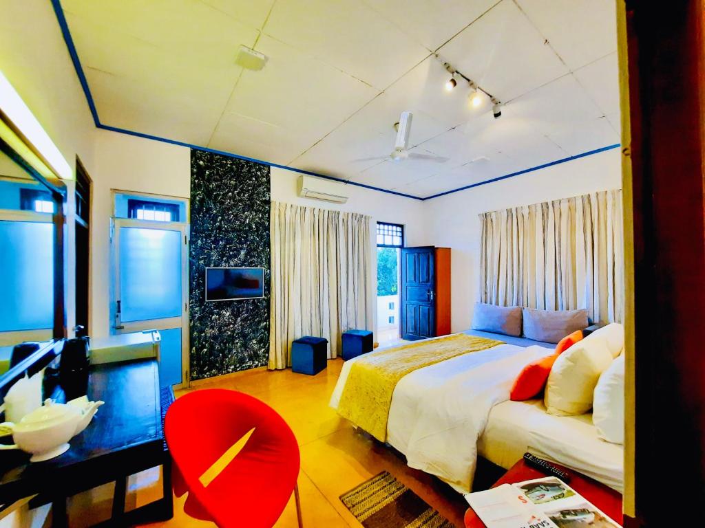 a bedroom with a large bed and a red chair at Hotel Dorset in Negombo