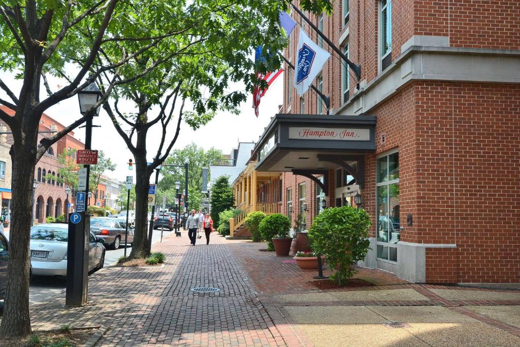 a brick building on a city street with people walking down the sidewalk at Hampton Inn Alexandria/Old Town in Alexandria