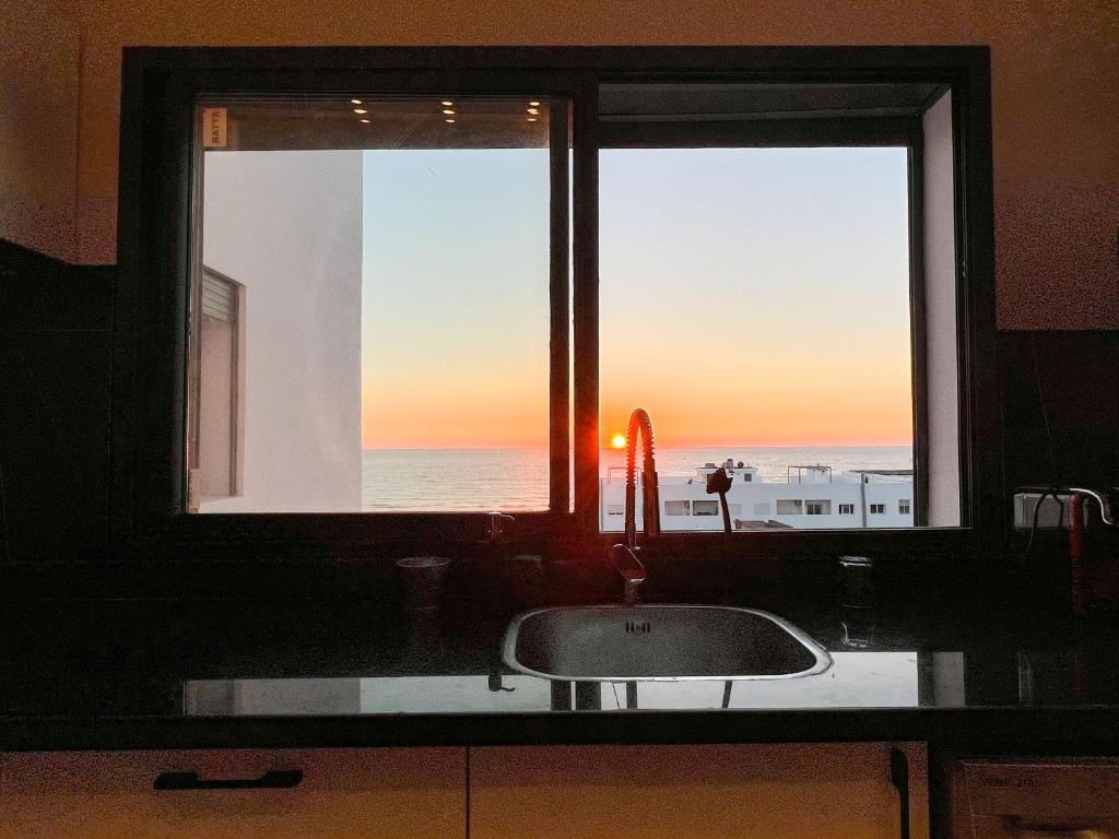 a kitchen window with a sink and a view of the ocean at Oasis Mehdia vue sur mer in Kenitra