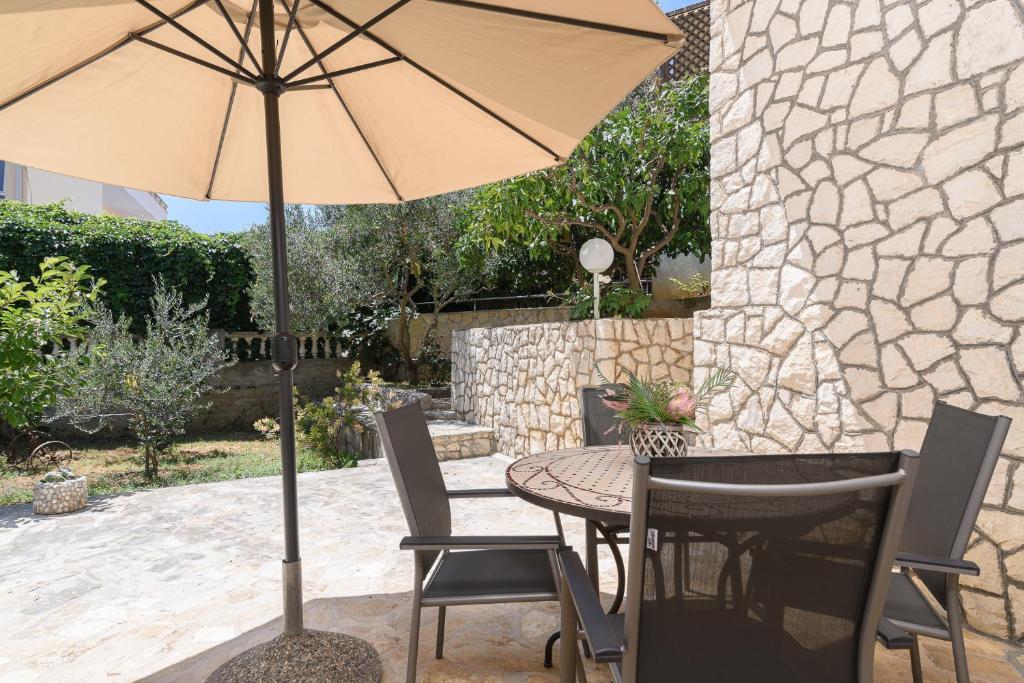 a table and chairs with an umbrella on a patio at Apartmani Šuki in Trogir