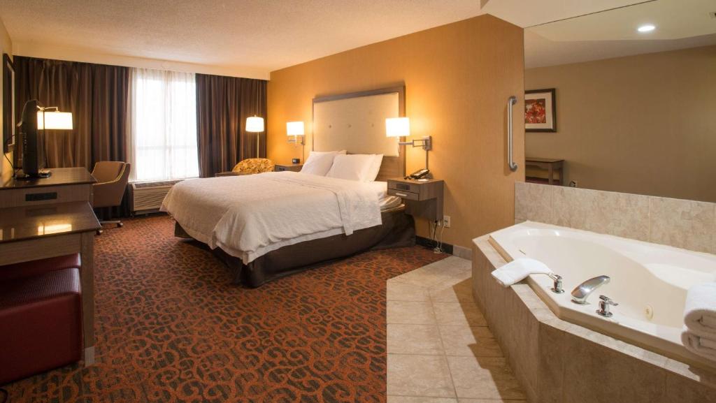 Habitación de hotel con cama y bañera en Hampton Inn Toronto-Mississauga West en Mississauga
