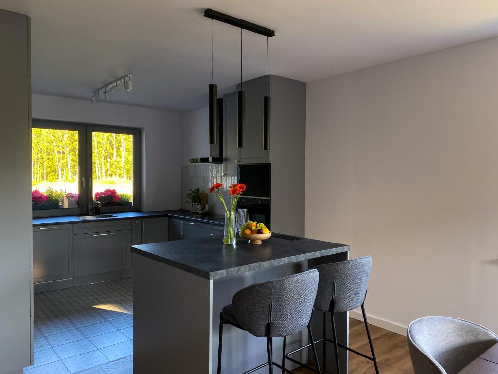 a kitchen with a black counter and some chairs at Dom na Wiklinowej in Dobrzewino