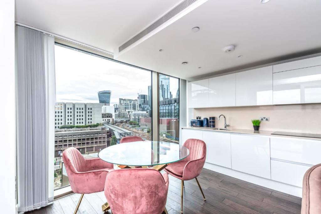 a kitchen with a glass table and pink chairs at Luxury 2 Bedroom Apartment in Tower Hill in London