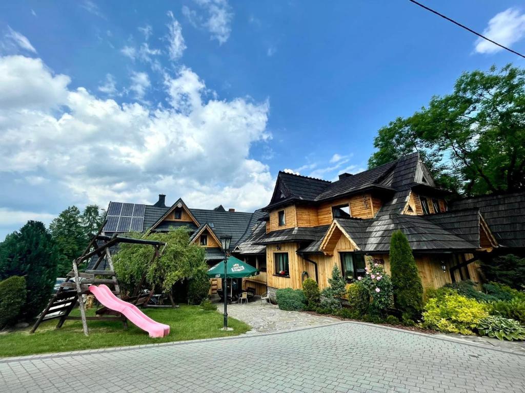 una casa con un tobogán y un parque infantil en Pokoje Goscinne u Naglaka Willa Zab en Ząb