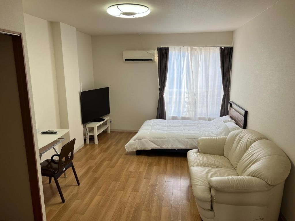 een slaapkamer met een bed, een bank en een televisie bij Wakatake Building Room 453 - Vacation STAY 53947v in Oita