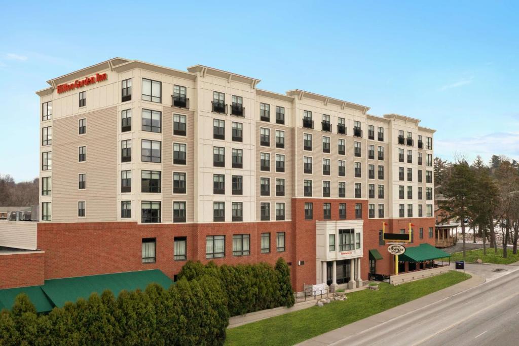 un grand bâtiment blanc sur le côté d'une rue dans l'établissement Hilton Garden Inn Troy, à Troy