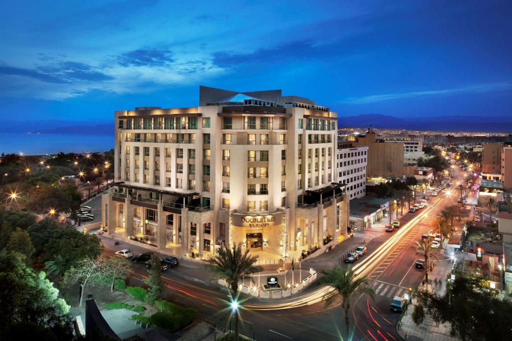 duży biały budynek na ulicy miejskiej w nocy w obiekcie DoubleTree by Hilton Hotel Aqaba w Akabie