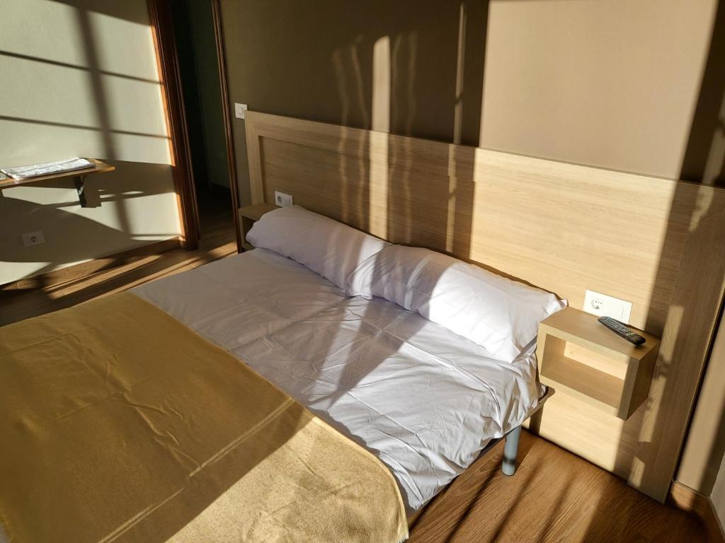 a small bed with white sheets and a night stand at CASA MARUXA pensión in Pontevedra