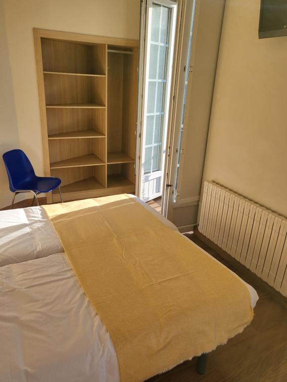 a bedroom with a bed and a blue chair at CASA MARUXA pensión in Pontevedra