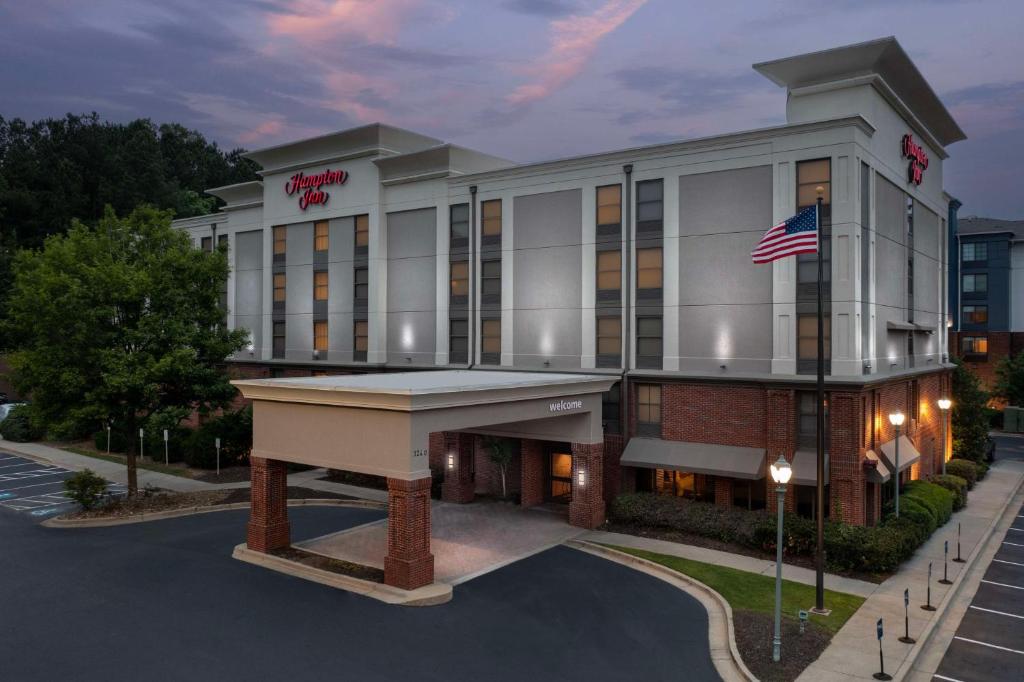 a hotel building with an american flag in front of it at Hampton Inn Atlanta-Mall Of Georgia in Buford