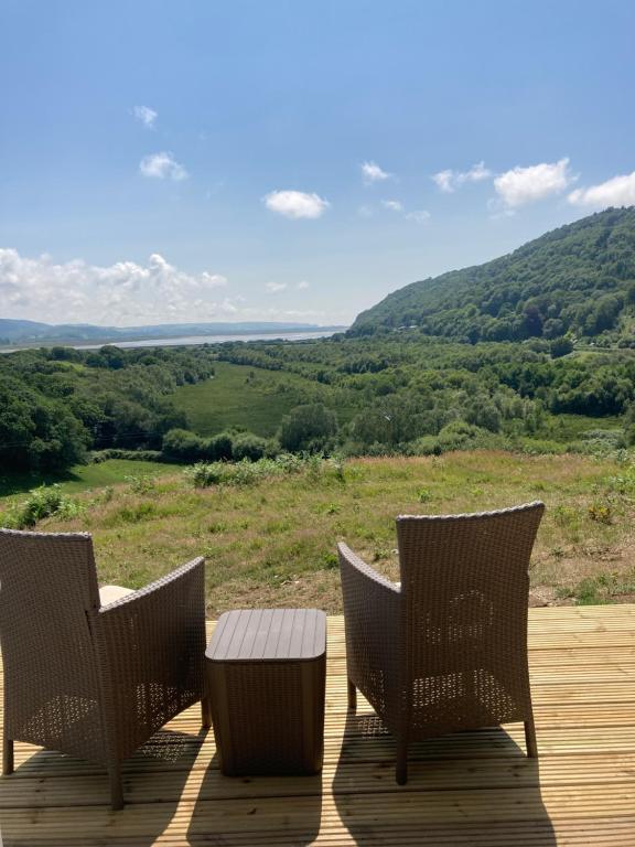 three chairs and a table on a deck with a view at Cefn Crib Cabins in Machynlleth