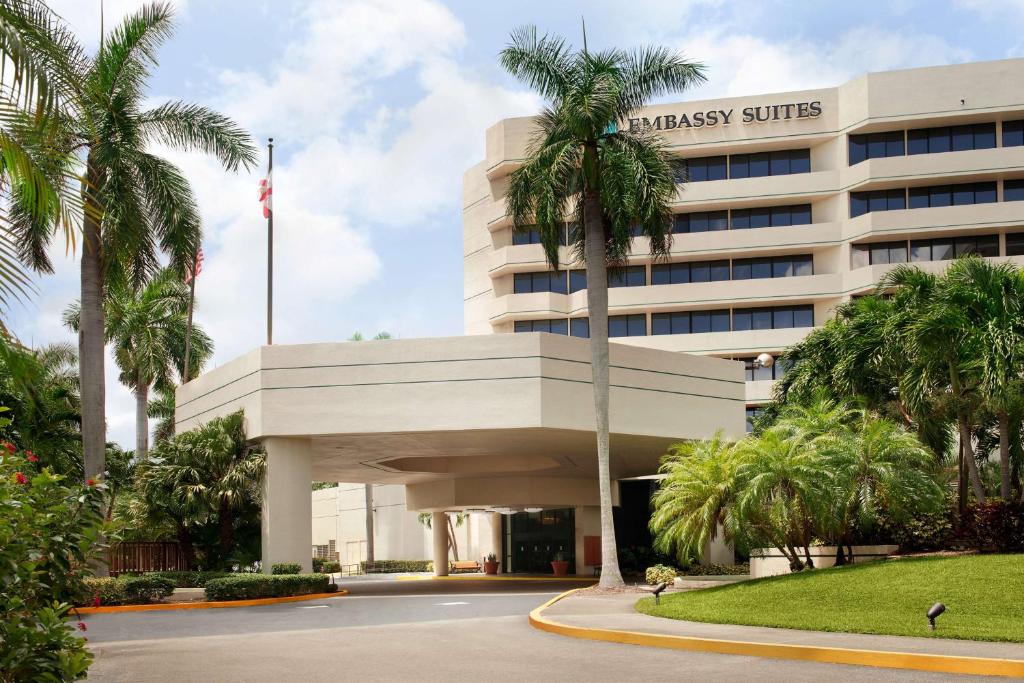 a hotel with palm trees in front of a building at Embassy Suites Boca Raton in Boca Raton