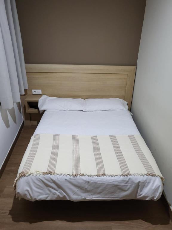 a bedroom with a bed with white sheets and pillows at CASA MARUXA pensión in Pontevedra