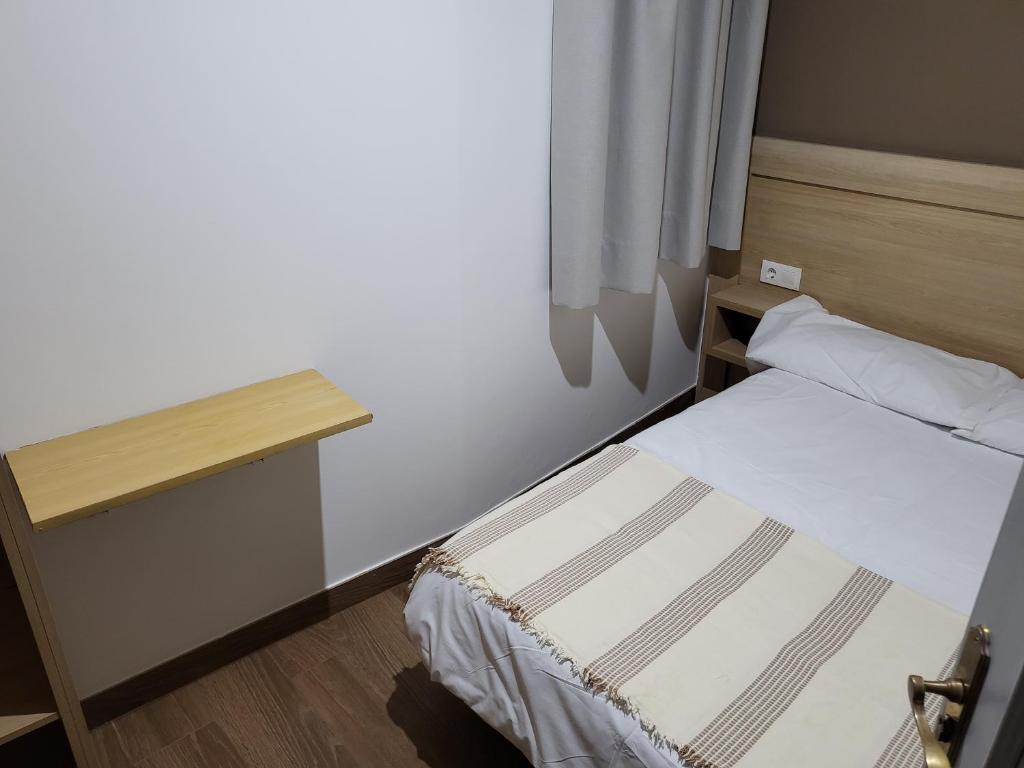 a small bedroom with a bed and a desk at CASA MARUXA pensión in Pontevedra