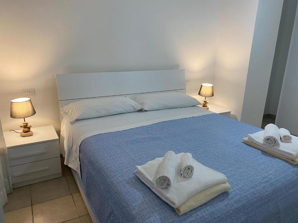 Un dormitorio con una cama azul con toallas. en Case sul mare, en Palau