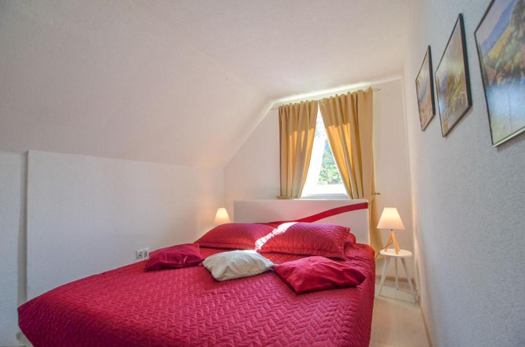 a bedroom with a red bed with a window at Planinska Oaza in Pale