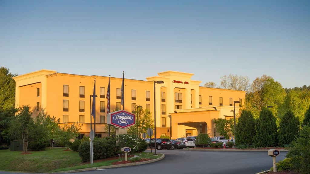 un grand bâtiment jaune avec un panneau devant lui dans l'établissement Hampton by Hilton Brattleboro, à Brattleboro