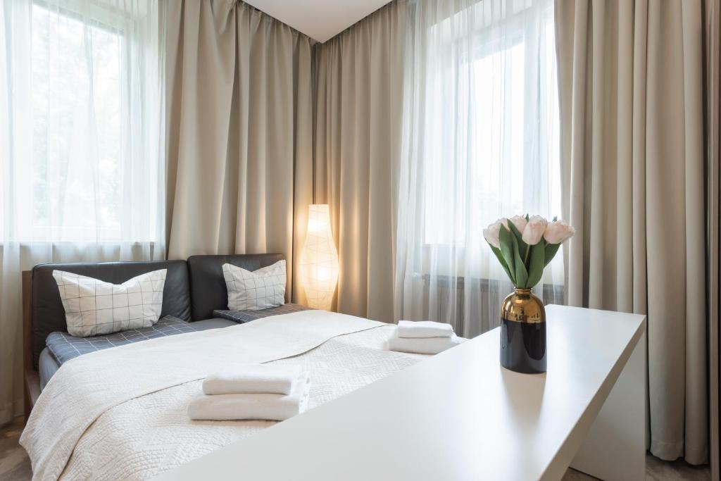een slaapkamer met een bed met een vaas met bloemen op een tafel bij GA - Bright and Stylish Apartment in the Center - Plac Konstytucji in Warschau
